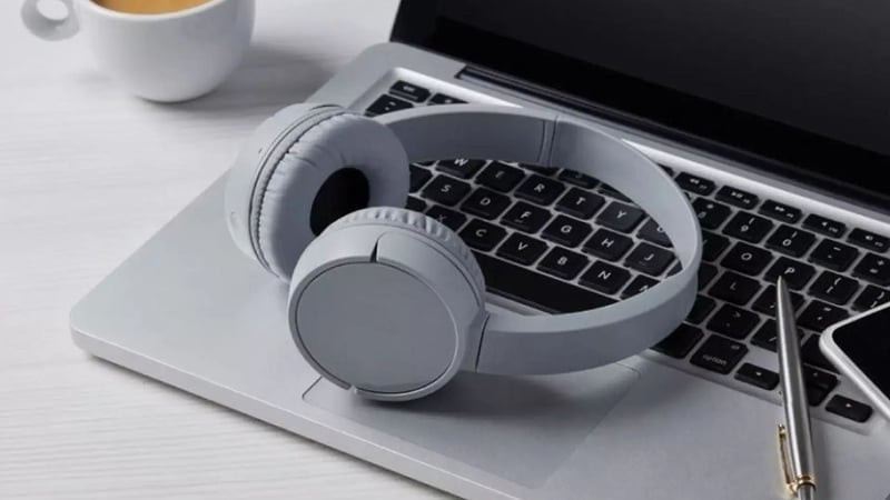 Người dùng đeo tai nghe chụp tai, tập trung vào màn hình máy tính